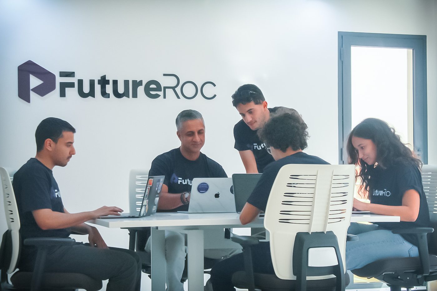 L'équipe FutureRoc travaillant ensemble autour d'une table au bureau de Tanger, sous le logo FutureRoc