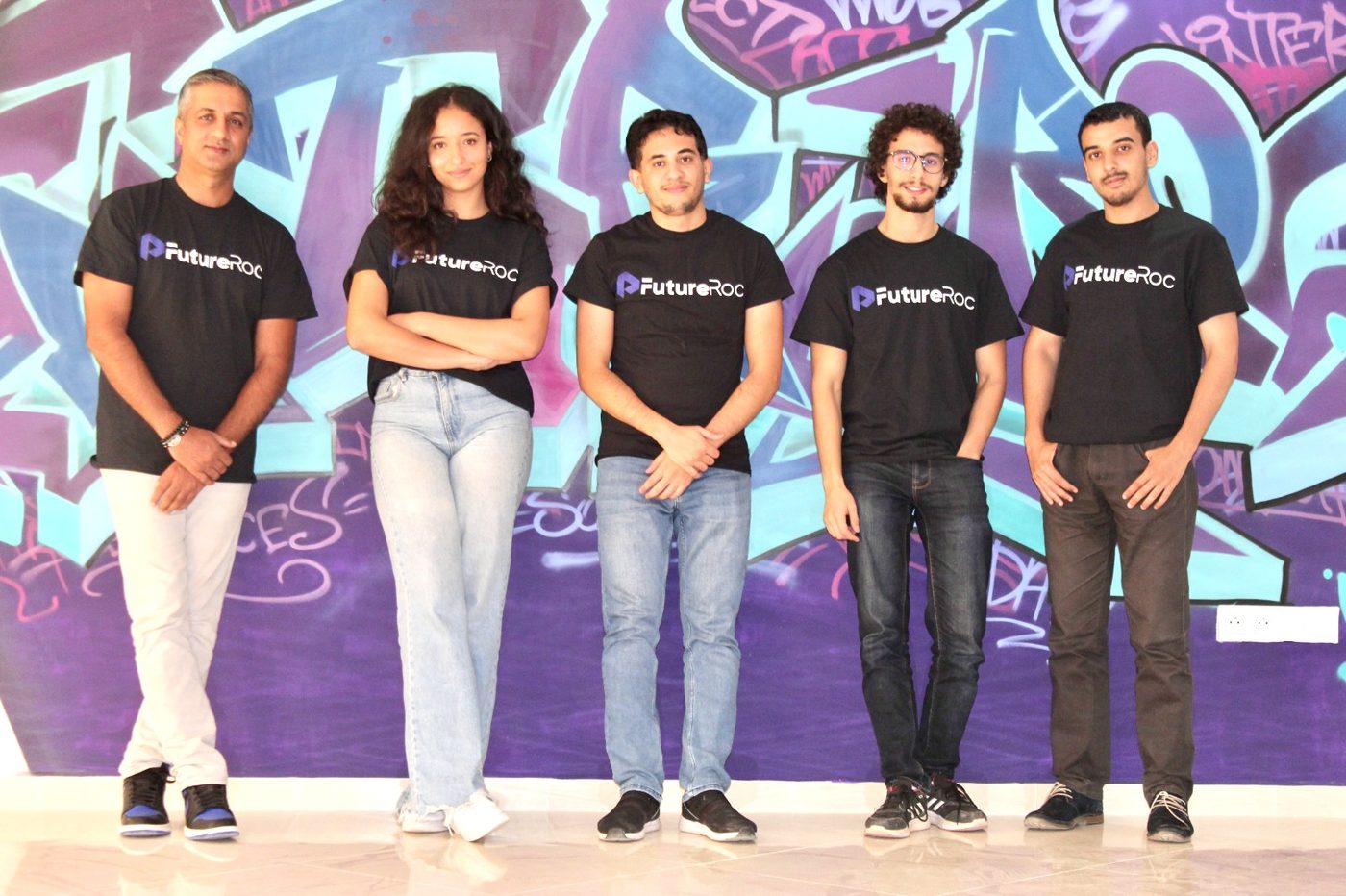 Les cinq membres de l'équipe FutureRoc devant un mur de graffitis, en t-shirts FutureRoc